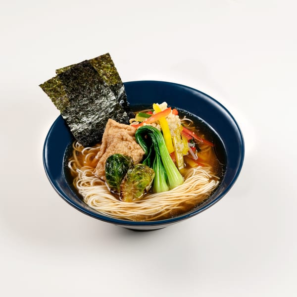 Taro's Japanese ramen with noodles, vegetables, tofu, and nori in a blue bowl.